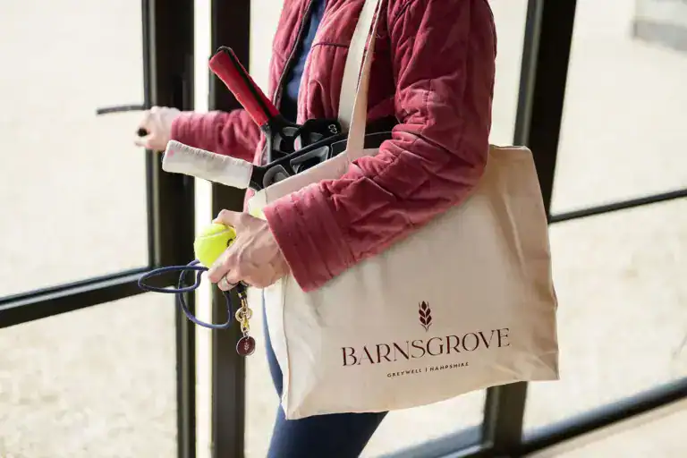 Woman carrying a bag with padel rackets at Barnsgrove Clubhouse – Palace Padel venue, ready for play at a premier UK padel tennis facility.