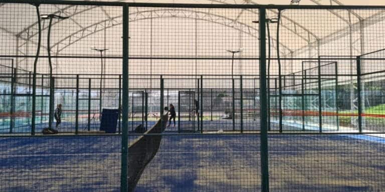 Huddersfield Lawn Tennis & Squash Club undercover courts with players on the back court and a sand-covered playing surface, showcasing the club’s versatile indoor facilities and active racquet sports scene in Huddersfield, West Yorkshire.