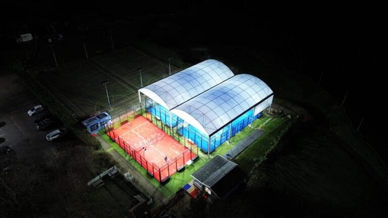 Night-time aerial view of Smash Padel Bicester HGS – two covered padel courts and one open-air court illuminated at a premier UK sports facility.