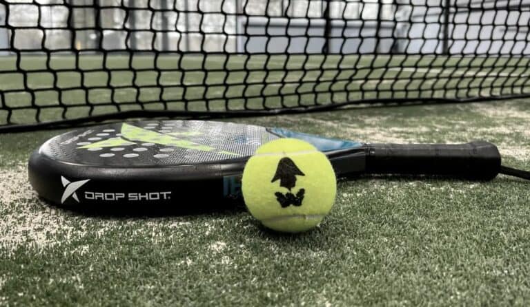 Padel racket and ball at The Barns at Wellington – close-up of equipment with padel court net in the background at a premier UK sports venue.