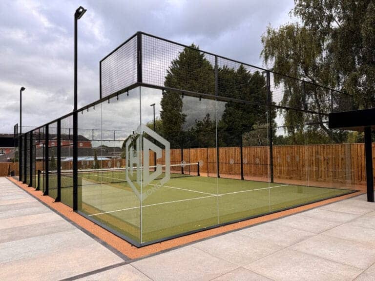 The Hook Club – open-air padel court with trees and fencing to the side and a house in the background at a countryside sports venue