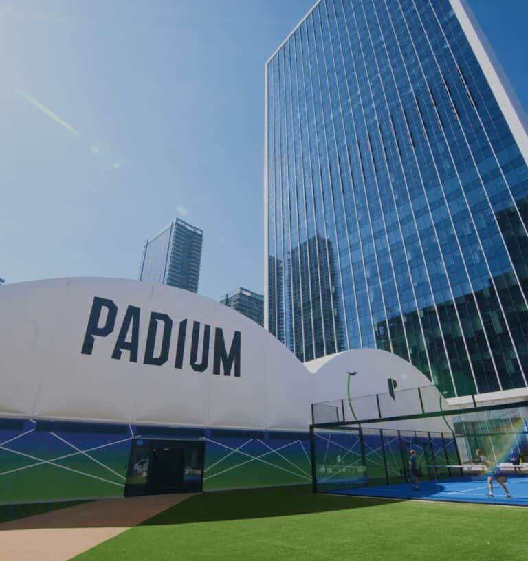 Padium Canary Wharf – outdoor padel court beside the main club building with office blocks in the background at a central London location